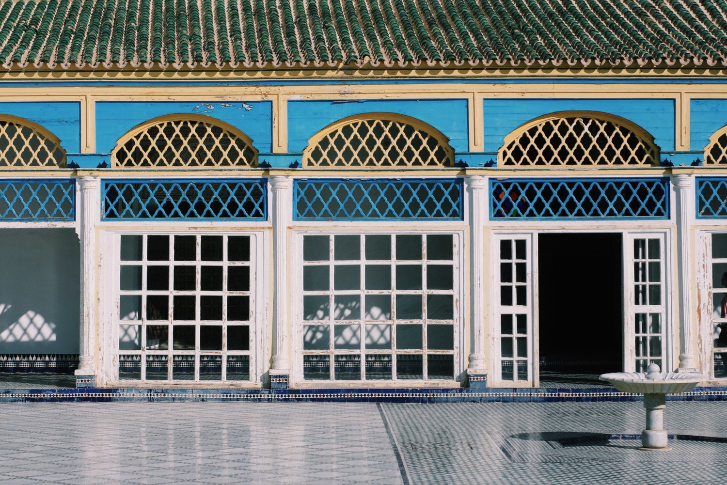 Bahia Palace courtyard facade with blue and yellow arched windows, Marrakesh