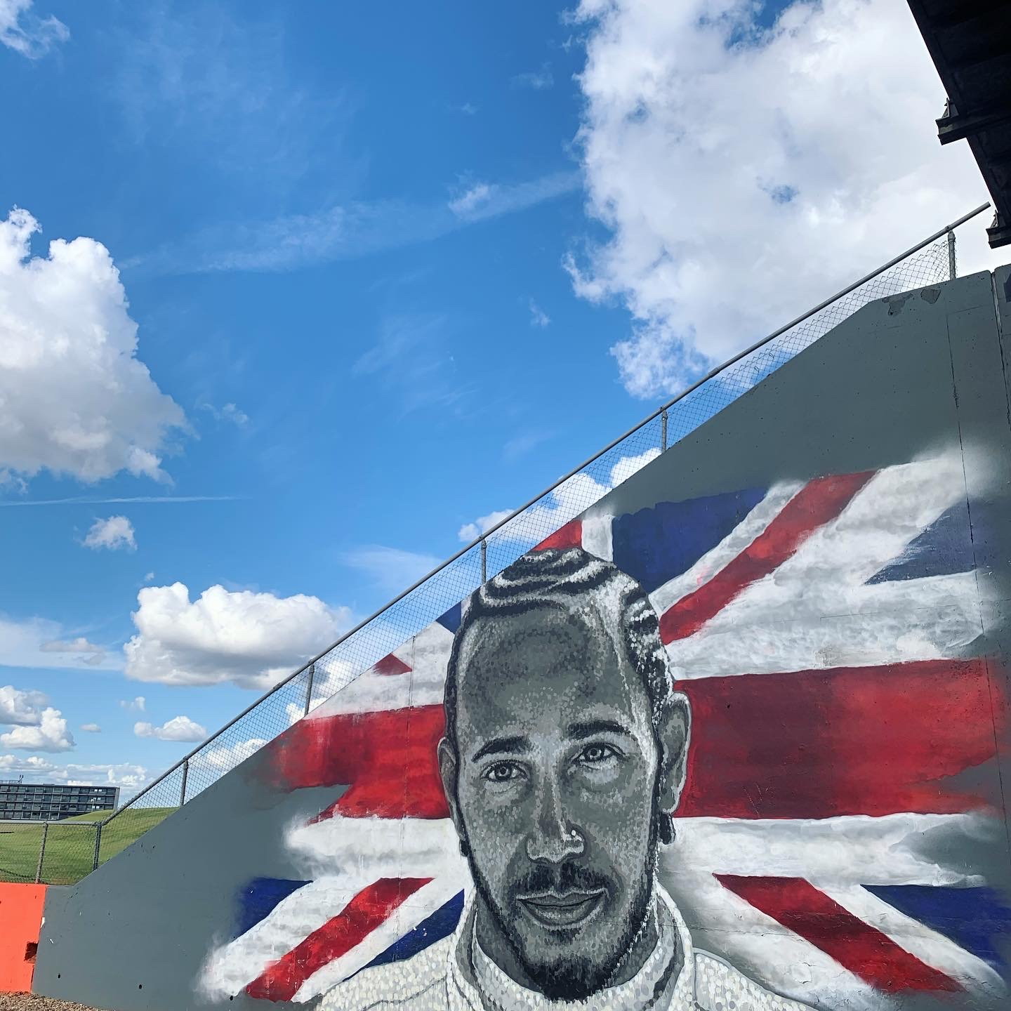 A painted mural of a driver against the Union flag, circuit wall