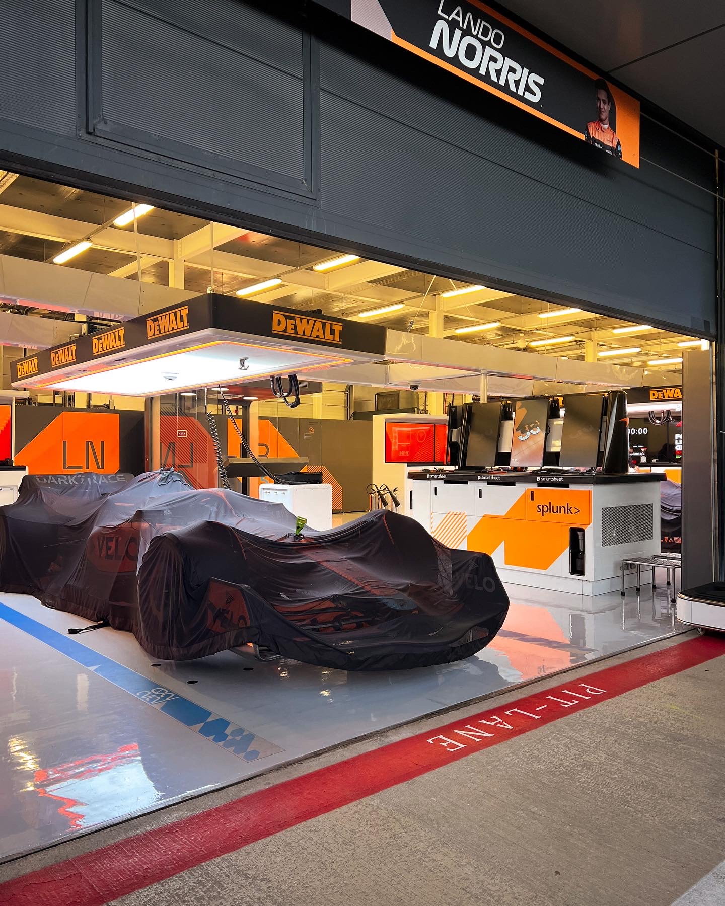 A covered car waiting in the pit lane under garage light
