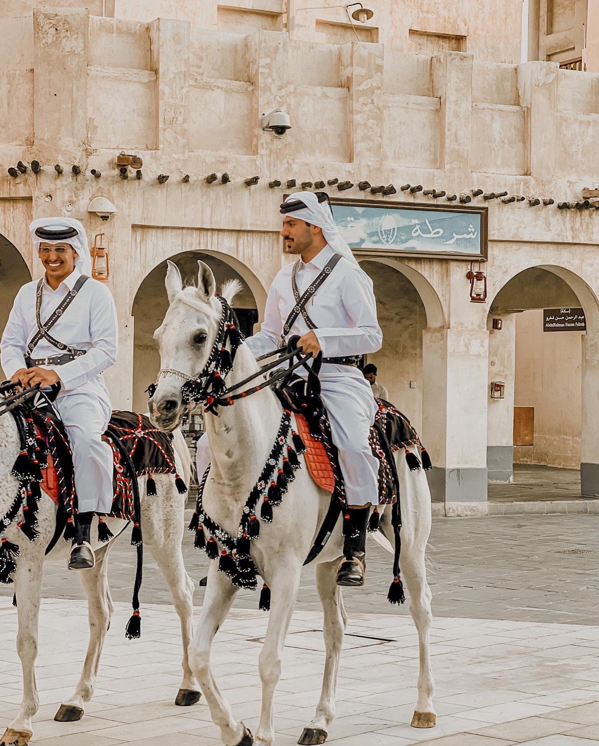 Mounted horsemen in white thobes on decorated horses at Souq Waqif, Doha