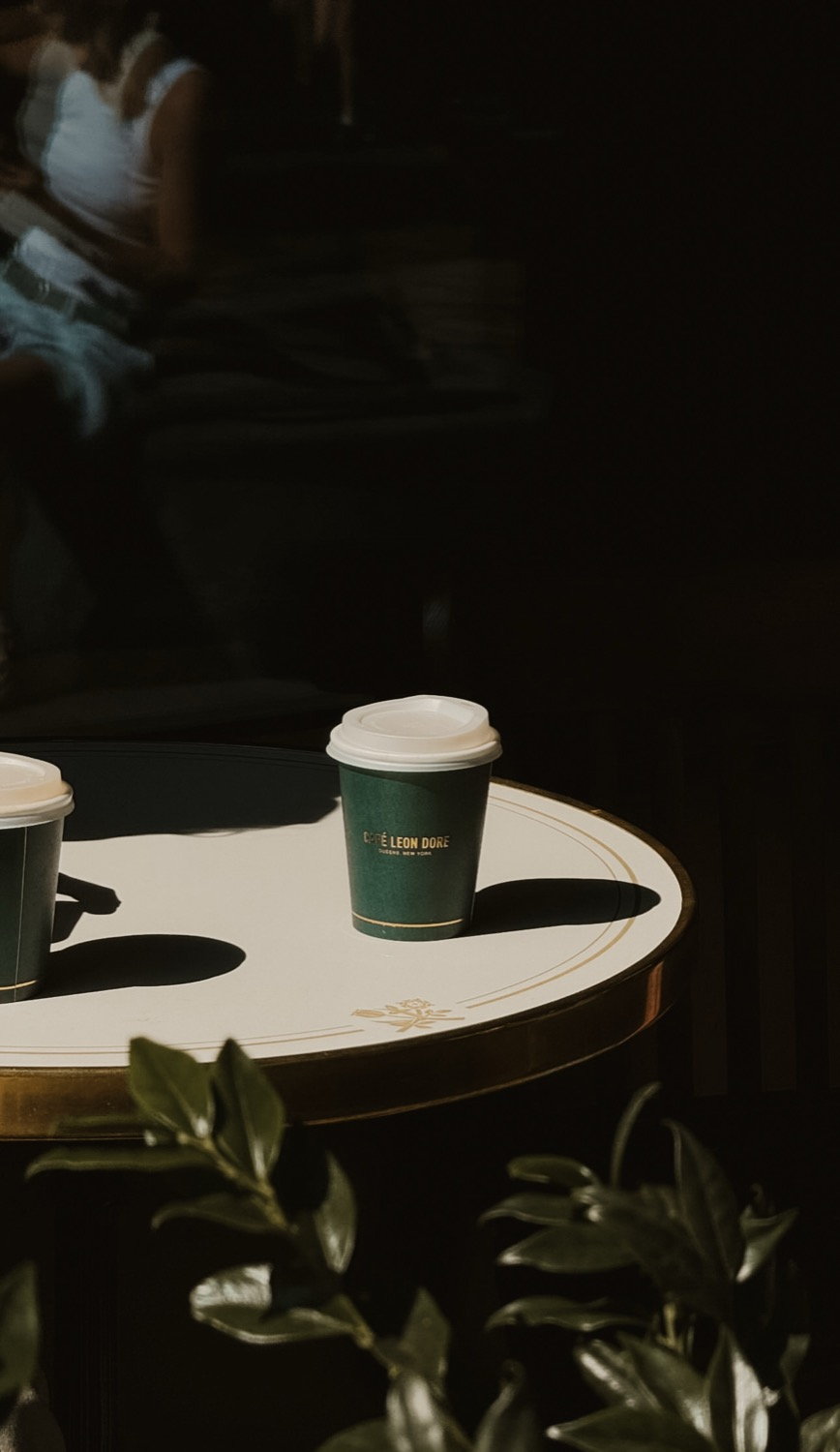 Café Leon Doré cup on a white and gold table in dark surroundings