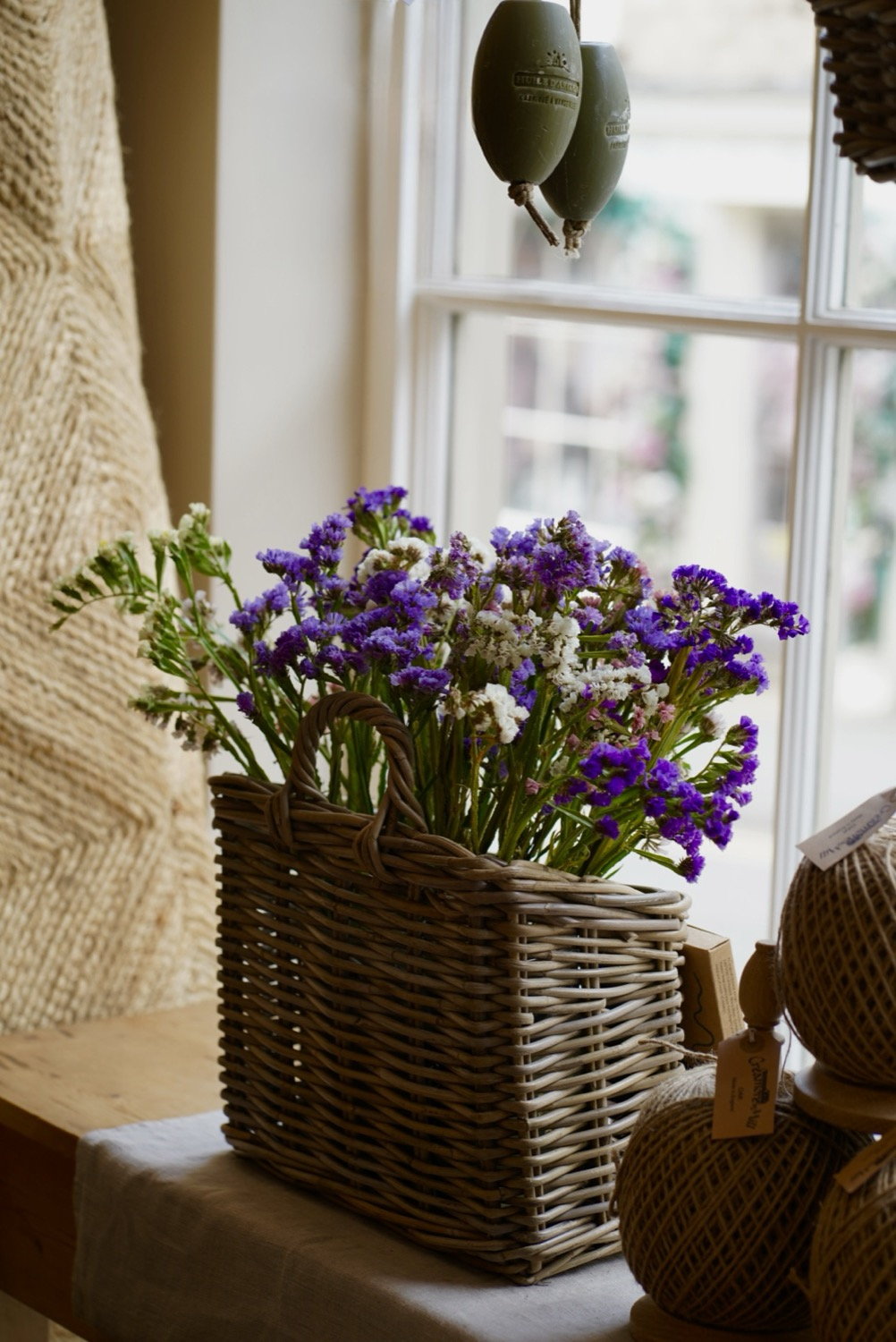 Purple statice flowers in a wicker basket by a shop window