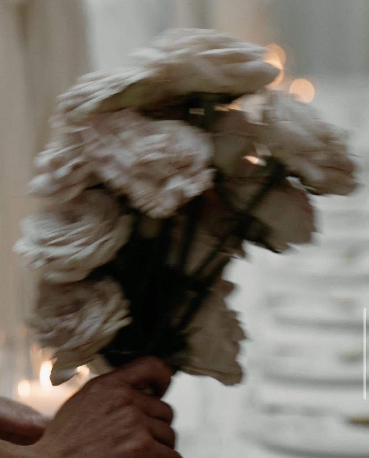 White garden roses held close, candle bokeh soft in the background