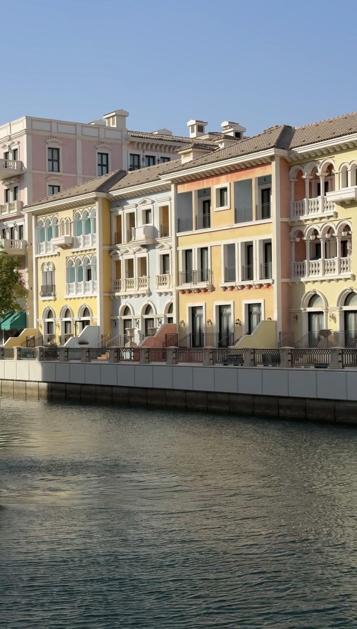 Yellow and coral facades along the canal edge, Qanat Quartier, Doha