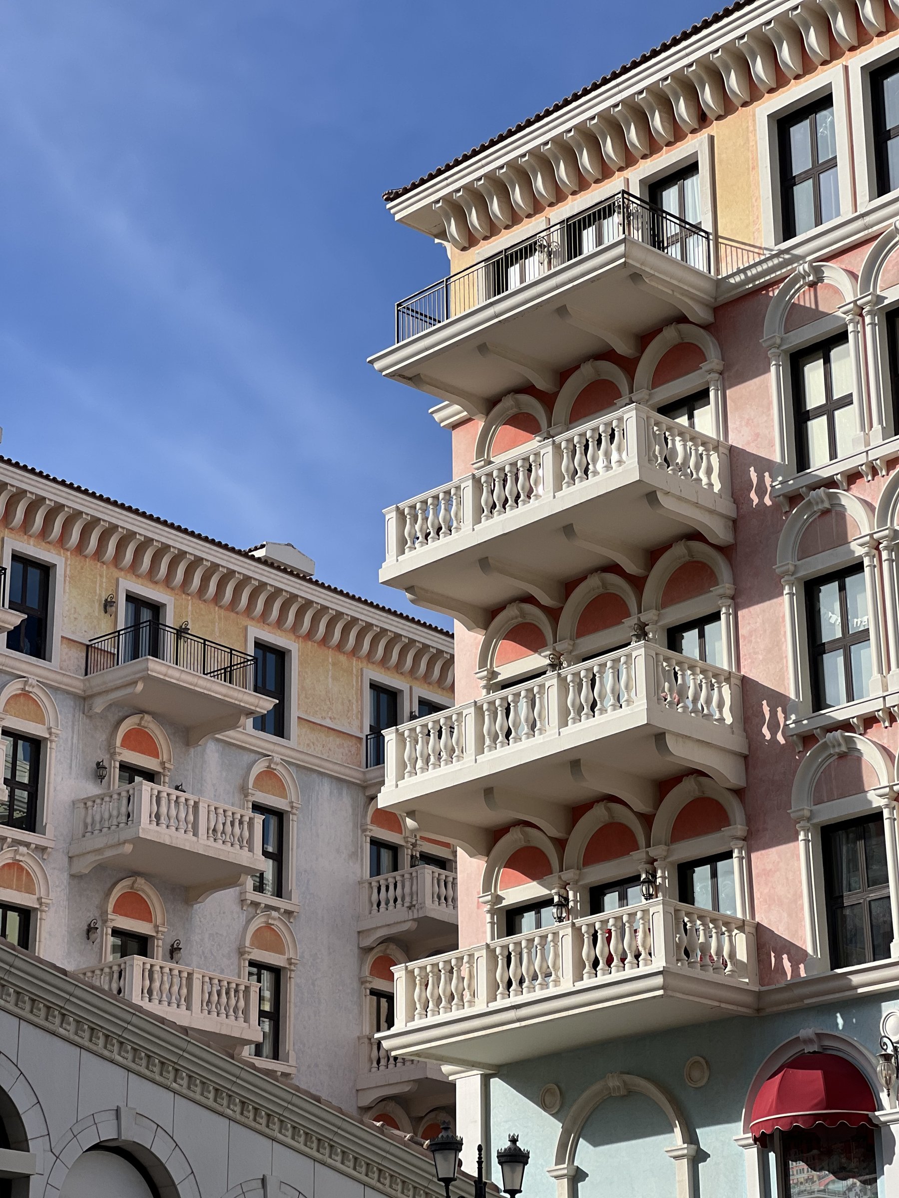 Pink arcaded balconies stacked against the light, Qanat Quartier, Doha