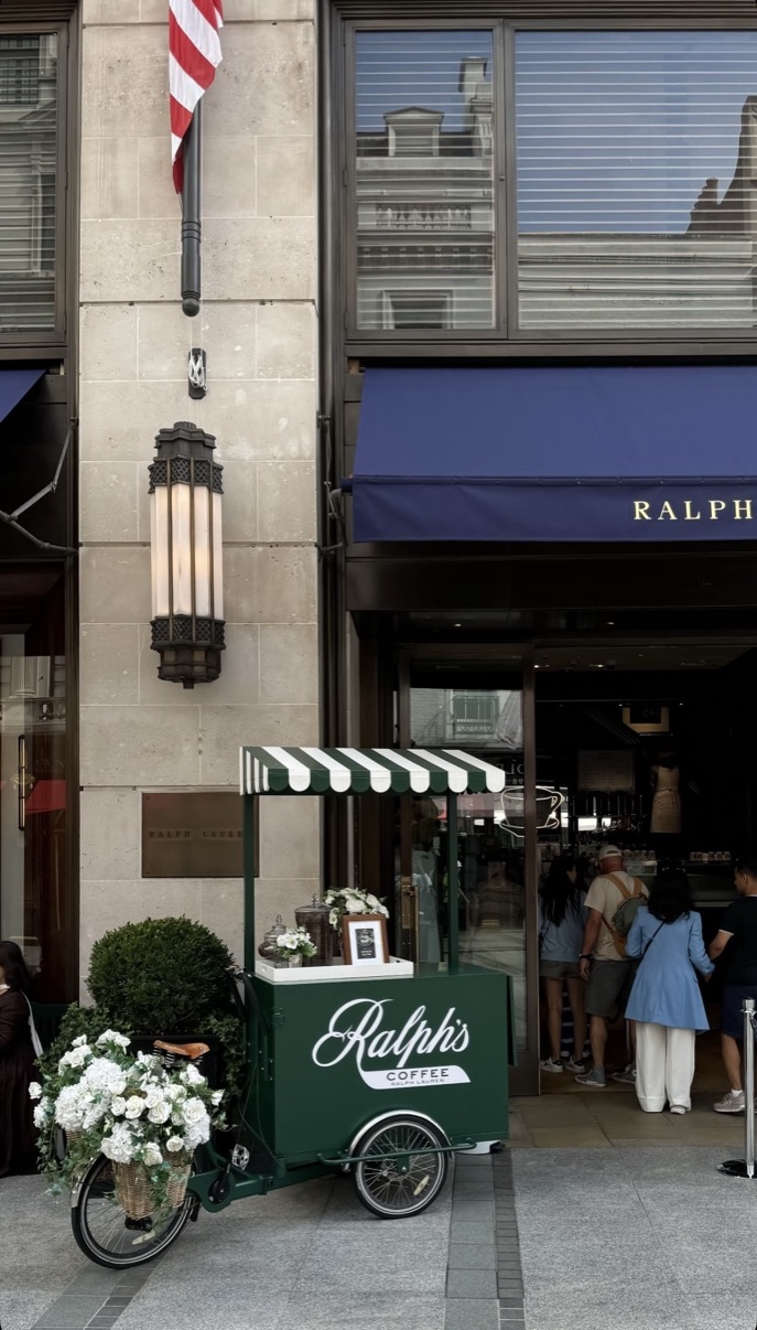 Green Ralph's Coffee cart with white flowers outside Ralph Lauren flagship entrance, London