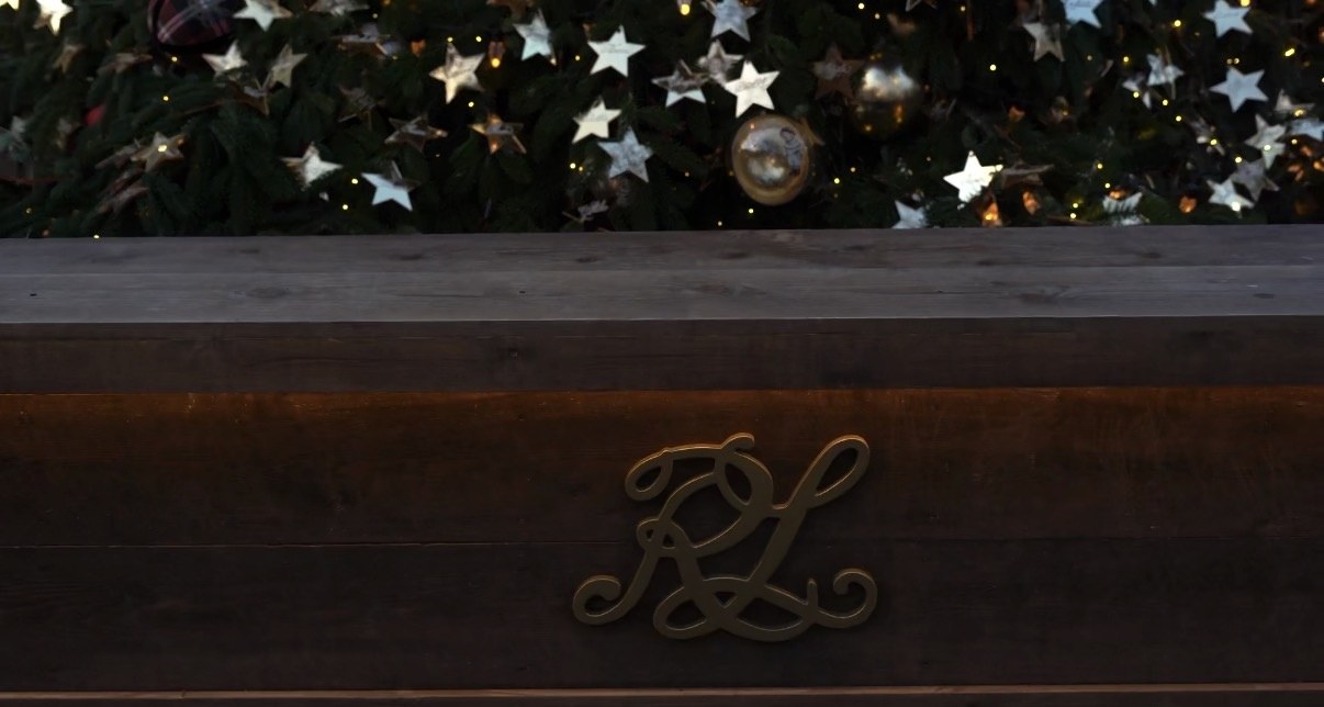A monogram in brass on a wooden bench, Christmas tree behind, London