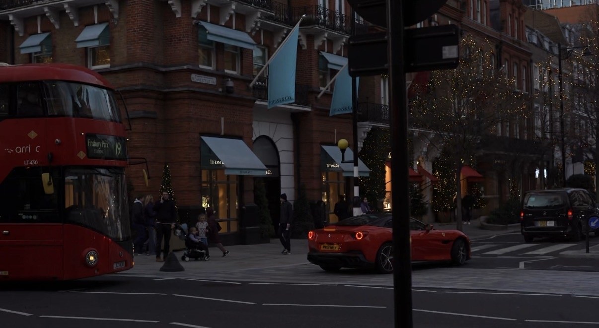 A bus and a red car move through the dusk past Tiffany and Co, London