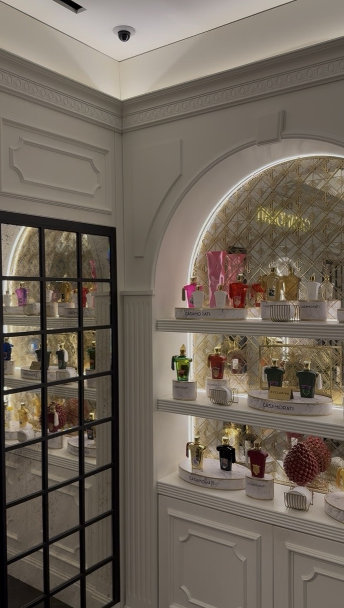 Arched perfume shelving niche with Casamorati bottles reflected in a glass door, Salon de Parfums, Harrods, London