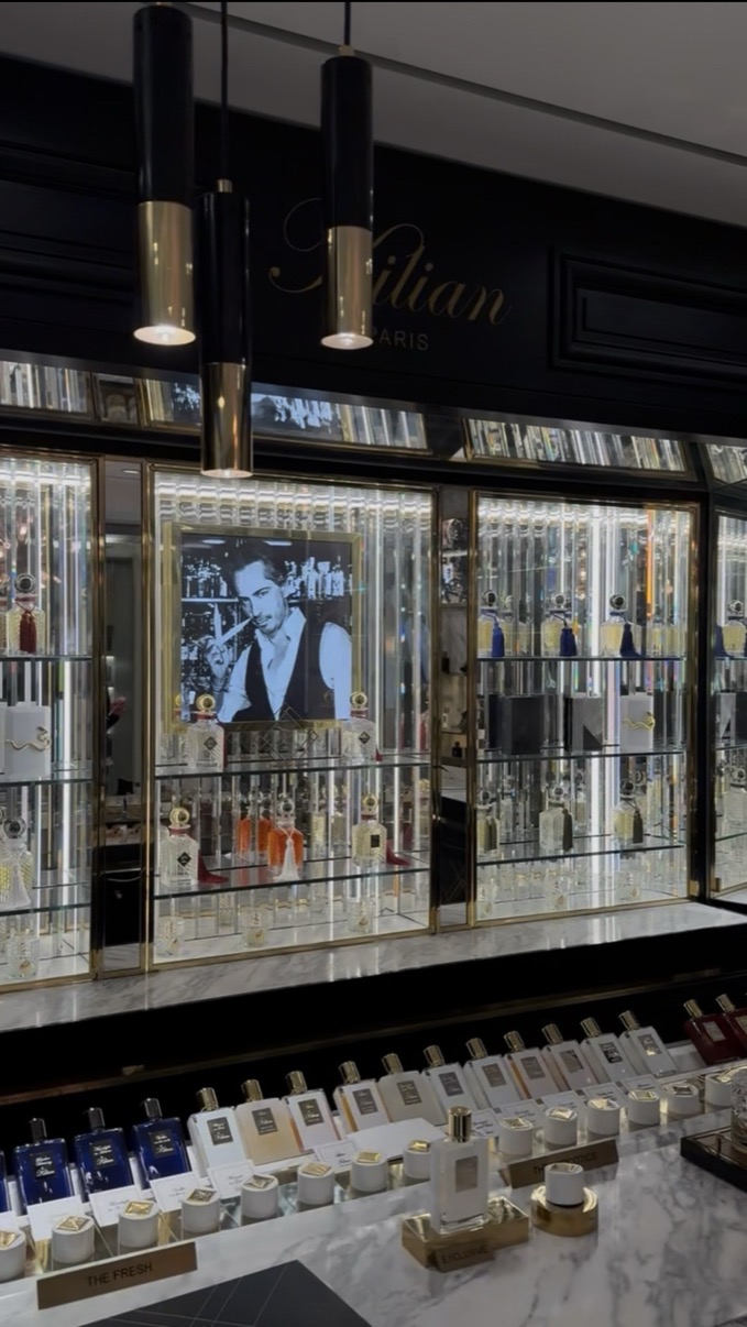 Kilian Paris dark lacquer cabinet with mirrored panels and rows of bottles on a marble counter, Salon de Parfums, Harrods, London