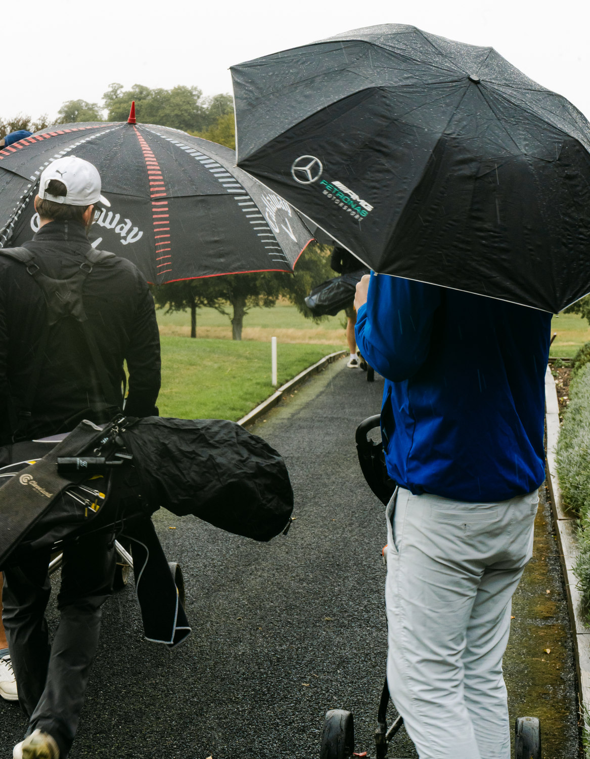 Umbrellas moving along the path in the rain, McLaren Construction Group Golf Day, Kent