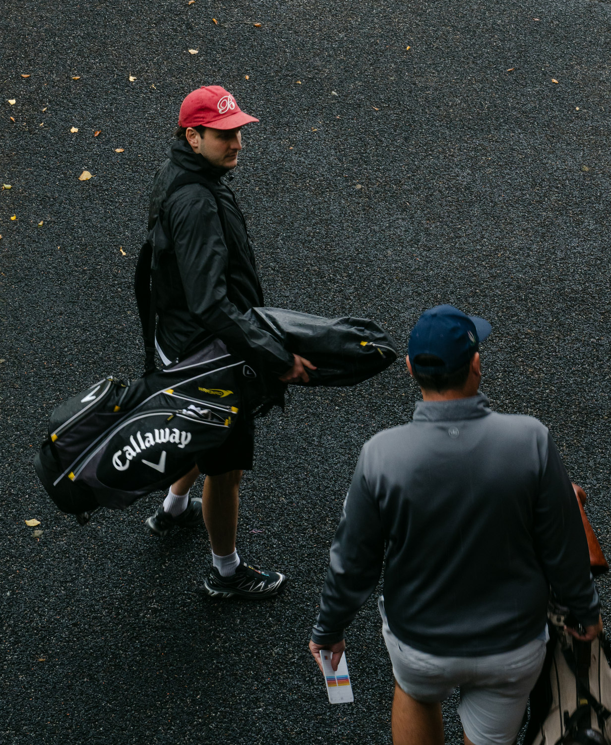 Two players carrying bags through the rain, McLaren Construction Group Golf Day, Kent