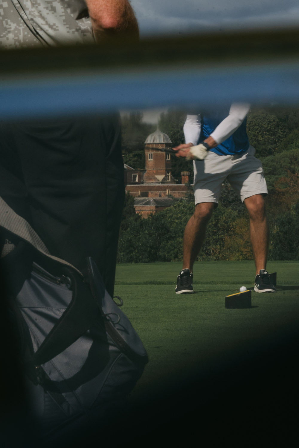 A player framed through the gap between a bag and a rail, McLaren Construction Group Golf Day, Kent