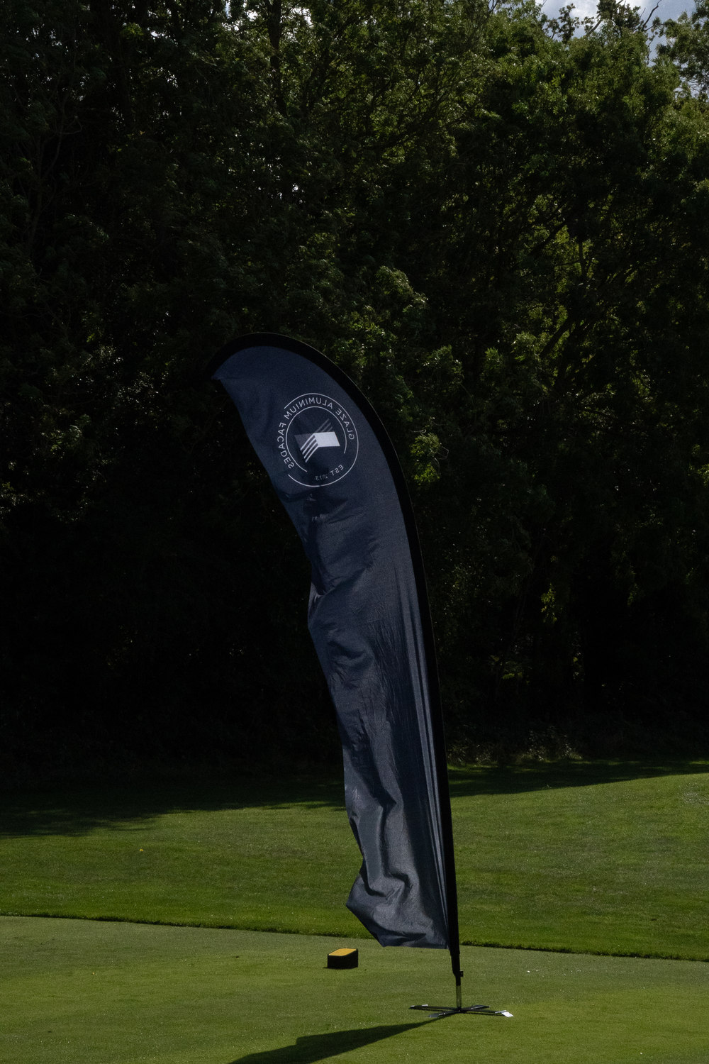 A partner banner standing against the trees, the green beyond, Rochester & Cobham Park, Kent