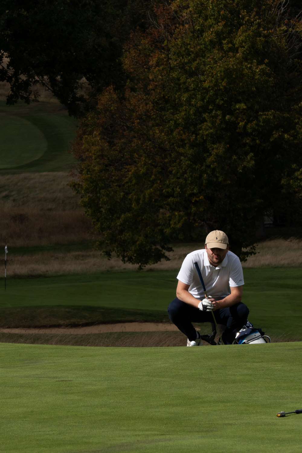 A player crouched low on the green, reading the line, McLaren Construction Group Golf Day, Kent