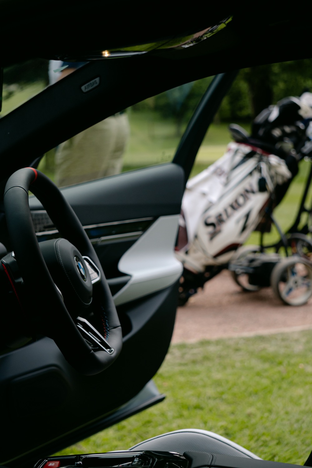 A golf bag waiting on a trolley, seen through the open door of a BMW, Magnolia Classic, Horsforth Golf Club, Leeds