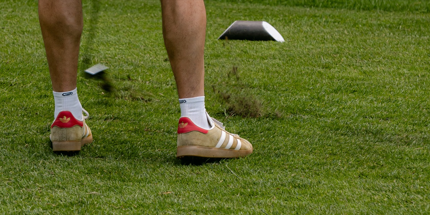 A pair of trainers set against the tee box as a drive is played, Magnolia Classic, Horsforth Golf Club, Leeds