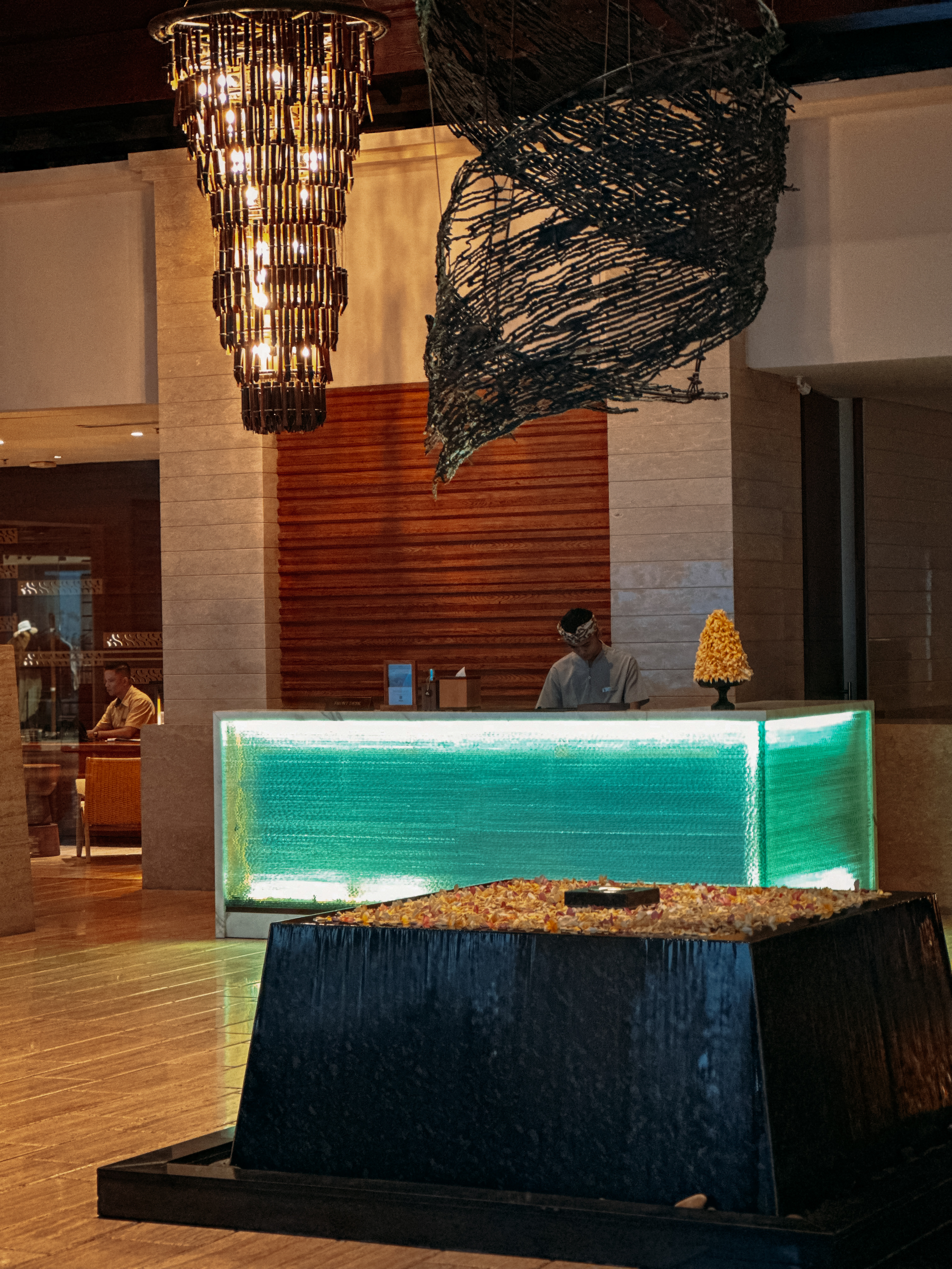 Reception desk glowing green, sculptural bird form suspended above, The Ritz-Carlton Bali