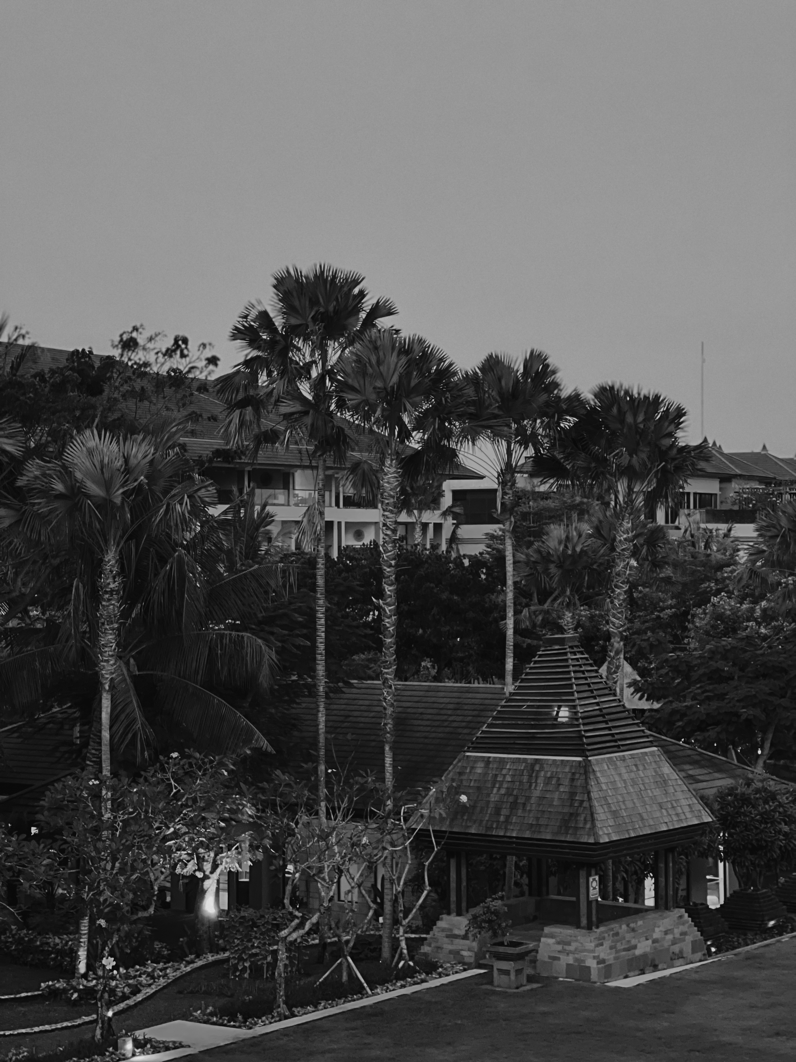 Tiered pavilion among palms at dusk, black and white, The Ritz-Carlton Bali