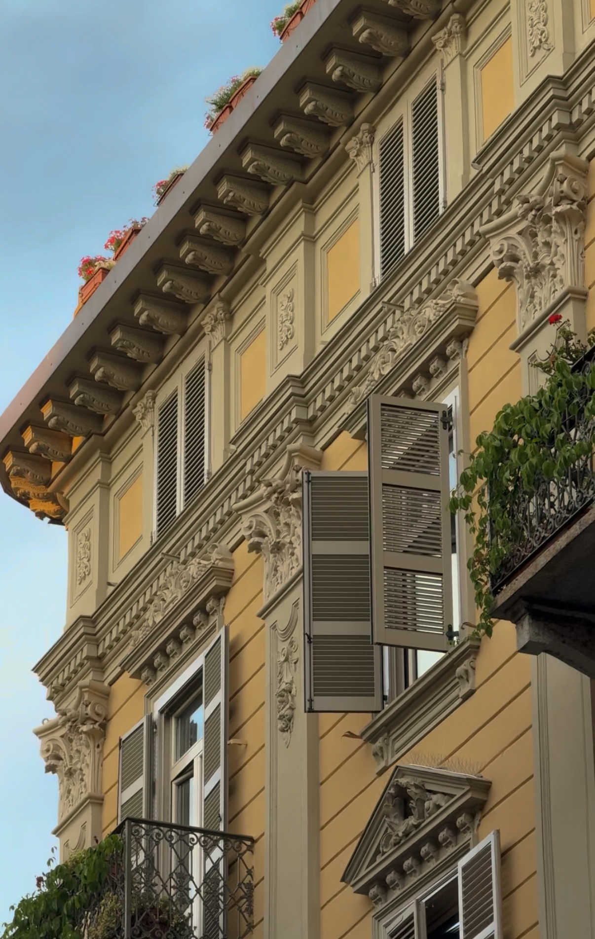 Ornate facade detail with open shutters and balconies, Turin